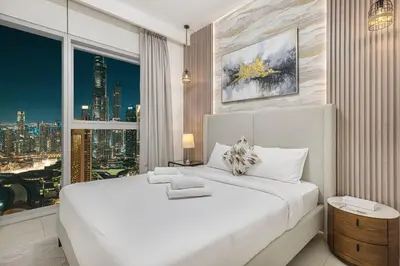 a bedroom with a large white bed and a window at Stylish 4BR with Burj & Fountain View, Dubai Mall Connection in Dubai