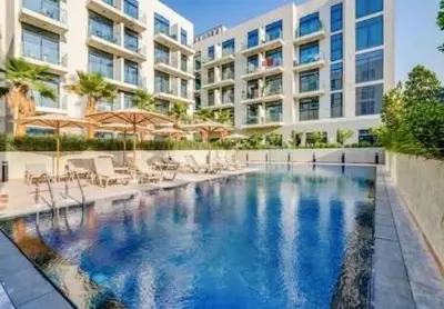 a swimming pool in front of a building at Chic Studio Living Elysee III by Pantheon in Dubai