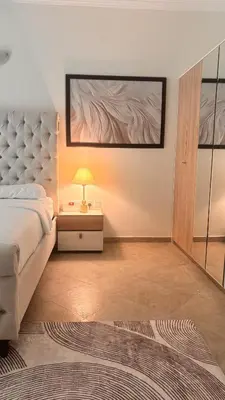 a bedroom with a bed and a table with a lamp at Miraclema Stays Al Barsha 1 in Dubai