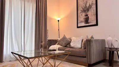 a living room with a couch and a glass table at Miraclema Stays Al Barsha 1 in Dubai