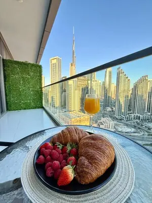 a plate of fruit and a croissant on a table with a drink at Luxury 2BR, Burj Khalifa View, Fully equipped, Top Amenities in Dubai