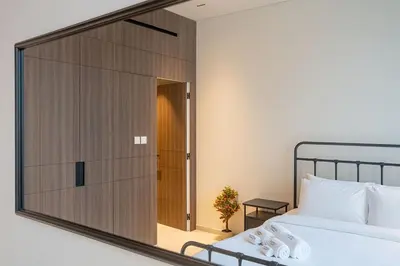 a mirror reflecting a bedroom with a bed and a door at Sleek New 1 Bed with Padel Court in Arjan in Dubai