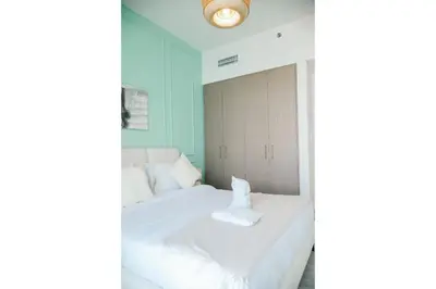 a bedroom with a white bed and a blue wall at HAVN - High Floor 2 bedroom in The Grand in Dubai