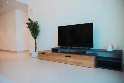 a flat screen tv sitting on top of a wooden entertainment center at HAVN - High Floor 2 bedroom in The Grand in Dubai