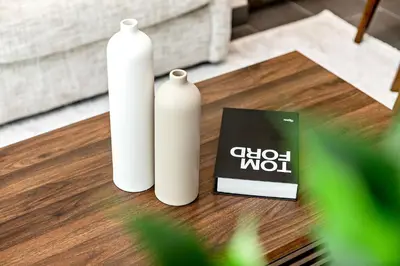 two white bottles sitting on a table with a book at Stylish 1BR Sobha The Crest Pool & City View in Dubai