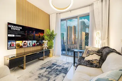 a living room with a tv and a large window at Spacious 1BR & Study Burj Khalifa View, Downtown in Dubai