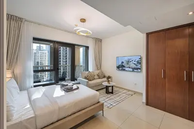 a bedroom with a bed and a couch and a window at Elegant studio balcony boulevard view in Dubai