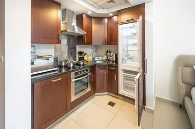 a kitchen with wooden cabinets and an open refrigerator at Elegant studio balcony boulevard view in Dubai