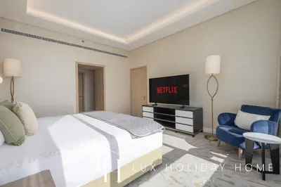 a bedroom with a bed and a tv and a chair at LUX Iconic Views at The Palm Tower Suite 7 in Dubai