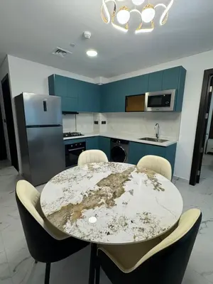 a kitchen with a table and chairs and blue cabinets at Opalz 1 bhk luxury apt for family and couple with swimming pool in Dubai