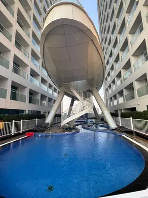 a large building with a swimming pool in front of it at Opalz 1 bhk luxury apt for family and couple with swimming pool in Dubai