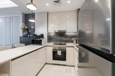 a kitchen with white cabinets and a stove at Modern Chic 1BHK Nobles Tower by Czechin in Dubai