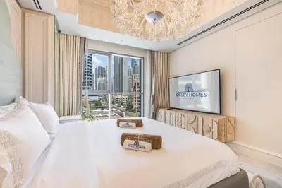 a bedroom with a large white bed with a chandelier at Chic Central Downtown Home with Burj View in Dubai