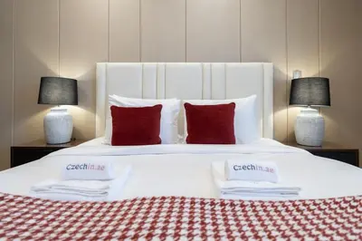 a large white bed with red pillows and two lamps at Stylish 1BHK Retreat at Nobles Tower, by Czechin in Dubai