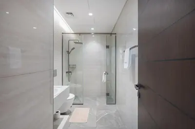 a bathroom with a glass shower and a toilet at Stylish 1BHK Retreat at Nobles Tower, by Czechin in Dubai