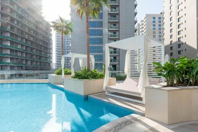 a large swimming pool with palm trees and buildings at Premium Apartment with Private Balcony Pool in Dubai