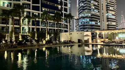 a large swimming pool in a city with tall buildings at Stunning Canal View Studio Business Bay in Dubai