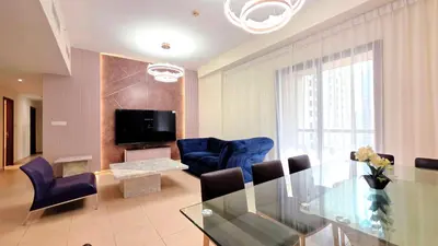 a living room with a glass table and blue chairs at Elan Rimal Bahar Suites, 1min walk to the Sea! Prime location JBR Beach Front in Dubai