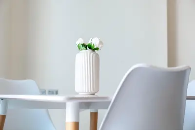 a white vase with white flowers on a table at Warm & Stylish Studio with Balcony in Dubai