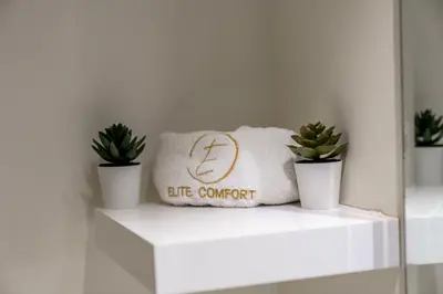 a white shelf with two potted plants on it at Warm & Stylish Studio with Balcony in Dubai