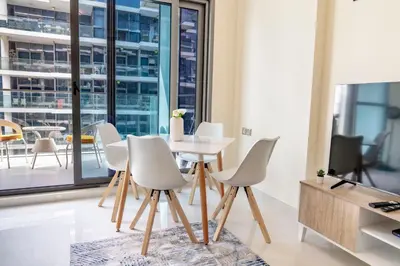 a dining room with a white table and chairs at Warm & Stylish Studio with Balcony in Dubai