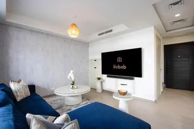a living room with a blue couch and a tv at 3BR Townhouse Rooftop Terrace Just Cavalli in Dubai