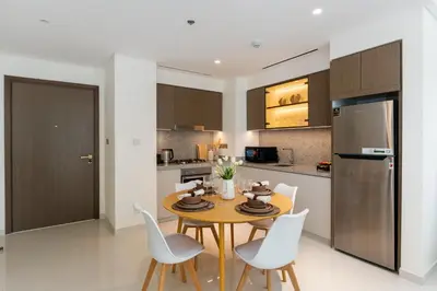 a kitchen with a wooden table and white chairs at Grand Bleu 1, Emaar Beachfront - Mint Stay in Dubai