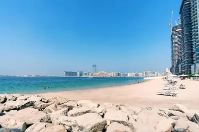 a beach with rocks in the water and buildings at Grand Bleu 1, Emaar Beachfront - Mint Stay in Dubai