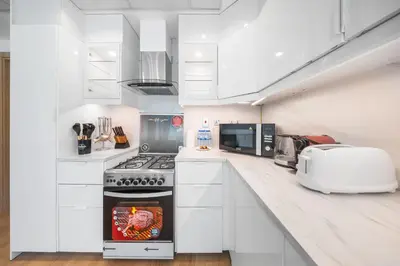 a white kitchen with a stove and a microwave at Luxury Spacious 5 bed Villa Pool and Garden in Dubai