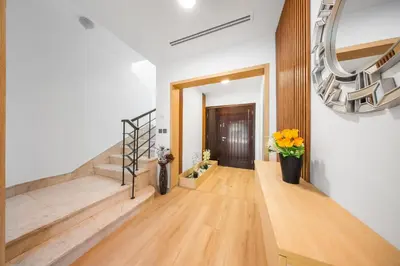 a hallway with wooden floors and a staircase with flowers at Luxury Spacious 5 bed Villa Pool and Garden in Dubai