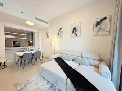a living room with a couch and a dining room at Cozy & Stylish 1BR in Wilton Terraces in Dubai