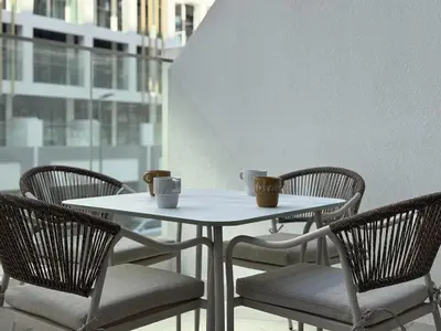 a white table and chairs with cups and mugs on it at Fresh & Modern Studio in Meydan - Azizi Riviera 67 in Dubai