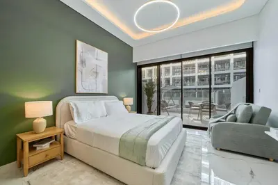a bedroom with a bed and a chair and a window at Fresh & Modern Studio in Meydan - Azizi Riviera 67 in Dubai