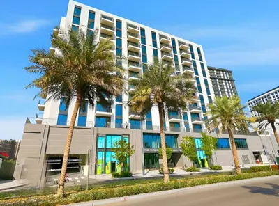 a building with palm trees in front of it at Elegant 2BR Close to Park in Park Horizon in Dubai