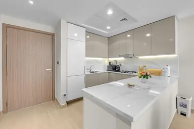 a white kitchen with a large white counter top at Stylish 1BR in Great Community in Dubai