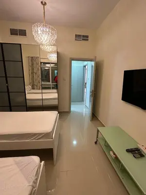 a room with two beds and a television and a chandelier at Large 2 BHK Apartment Next to DMCC Metro Station in Dubai