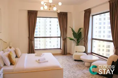 a large room with a bed and two large windows at Cloud 9 - Steps to the Beach Elegant 2BR in JBR in Dubai