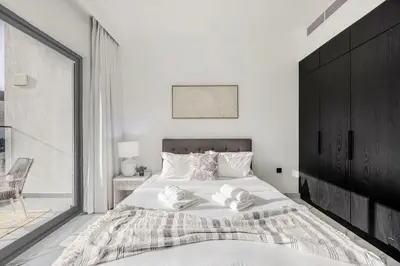 a white bedroom with a large bed and a window at Chic 2BR Haven in Prime Location in Gardenia Living in Dubai