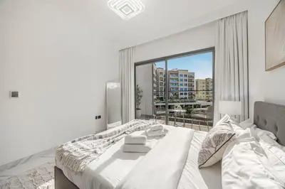 a bedroom with a bed and a large window at Chic 2BR Haven in Prime Location in Gardenia Living in Dubai