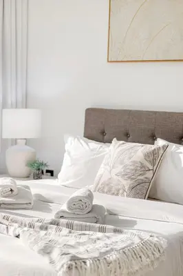 a bed with white sheets and towels on it at Chic 2BR Haven in Prime Location in Gardenia Living in Dubai