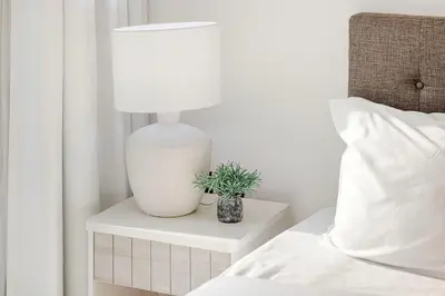a white lamp on a night stand next to a bed at Chic 2BR Haven in Prime Location in Gardenia Living in Dubai