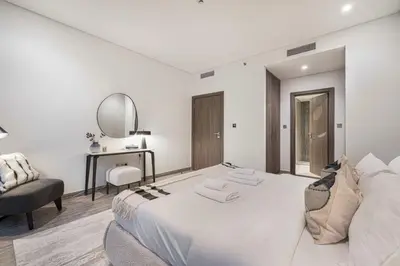a white bedroom with a bed and a mirror at StayMada - Peninsula Exclusive Canal Front Retreat in Dubai