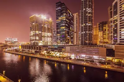 a city with tall buildings and a river at night at StayMada - Peninsula Exclusive Canal Front Retreat in Dubai