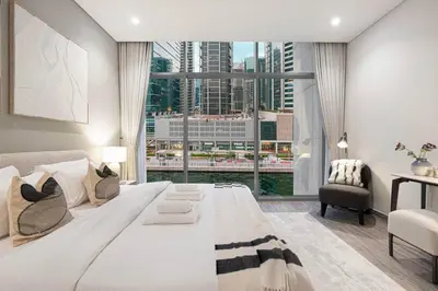 a bedroom with a large bed and a large window at StayMada - Peninsula Exclusive Canal Front Retreat in Dubai