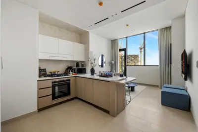 a kitchen with white cabinets and a large window at Stylish 1BR with Private Pool Near Circle Mall in Dubai