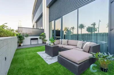 a patio with a couch and a table on the grass at Cloud 9 - Townhouse style 2 BR Apt with BBQ Patio in Dubai