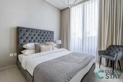 a bedroom with a large bed and a chair at Cloud 9 - Townhouse style 2 BR Apt with BBQ Patio in Dubai