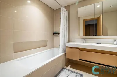 a bathroom with a tub and a sink and a mirror at Cloud 9 - Townhouse style 2 BR Apt with BBQ Patio in Dubai
