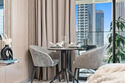 a table with two chairs in a room with a window at The Smart Concierge - Peninsula One in Dubai