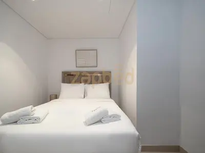 a white bed with two towels on top of it at Zapbed House Luxury 2BR at Boulevard Point Walk to Dubai Mall in Dubai
